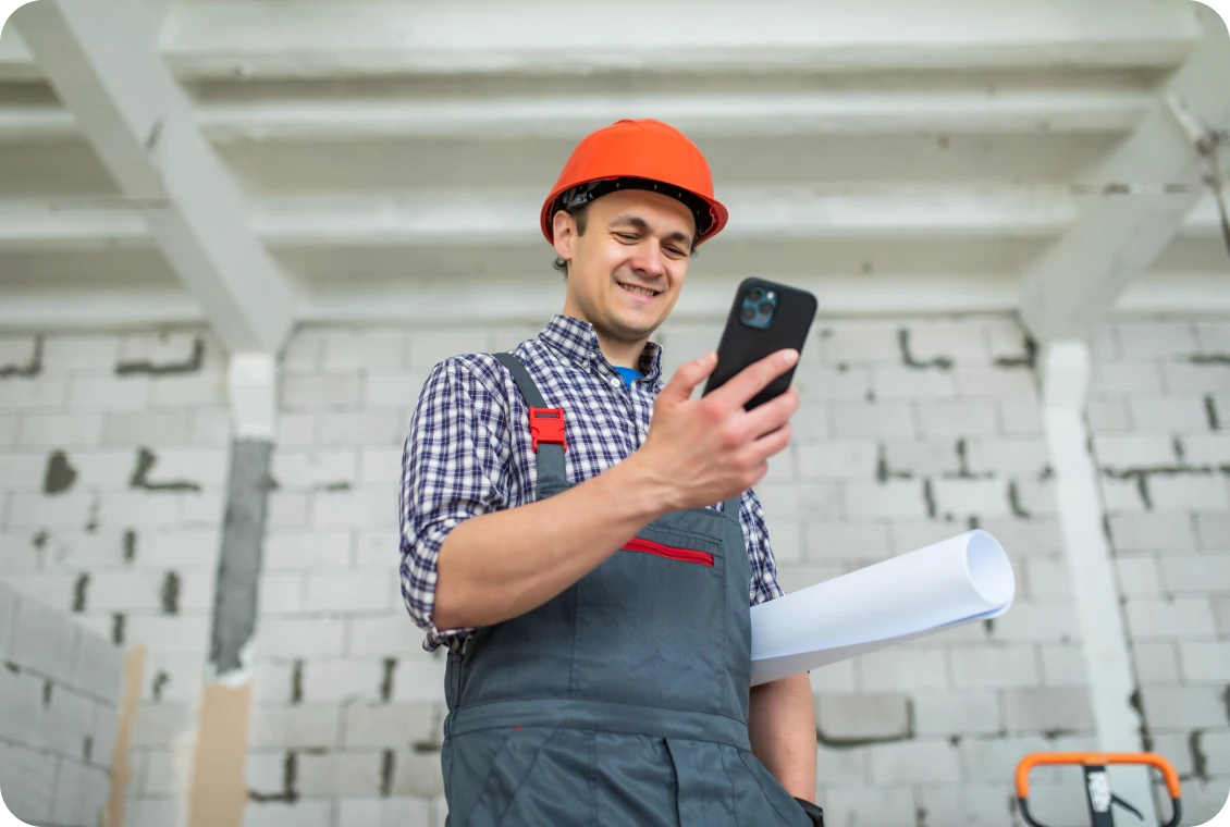 Builder holding blueprint and smartphone